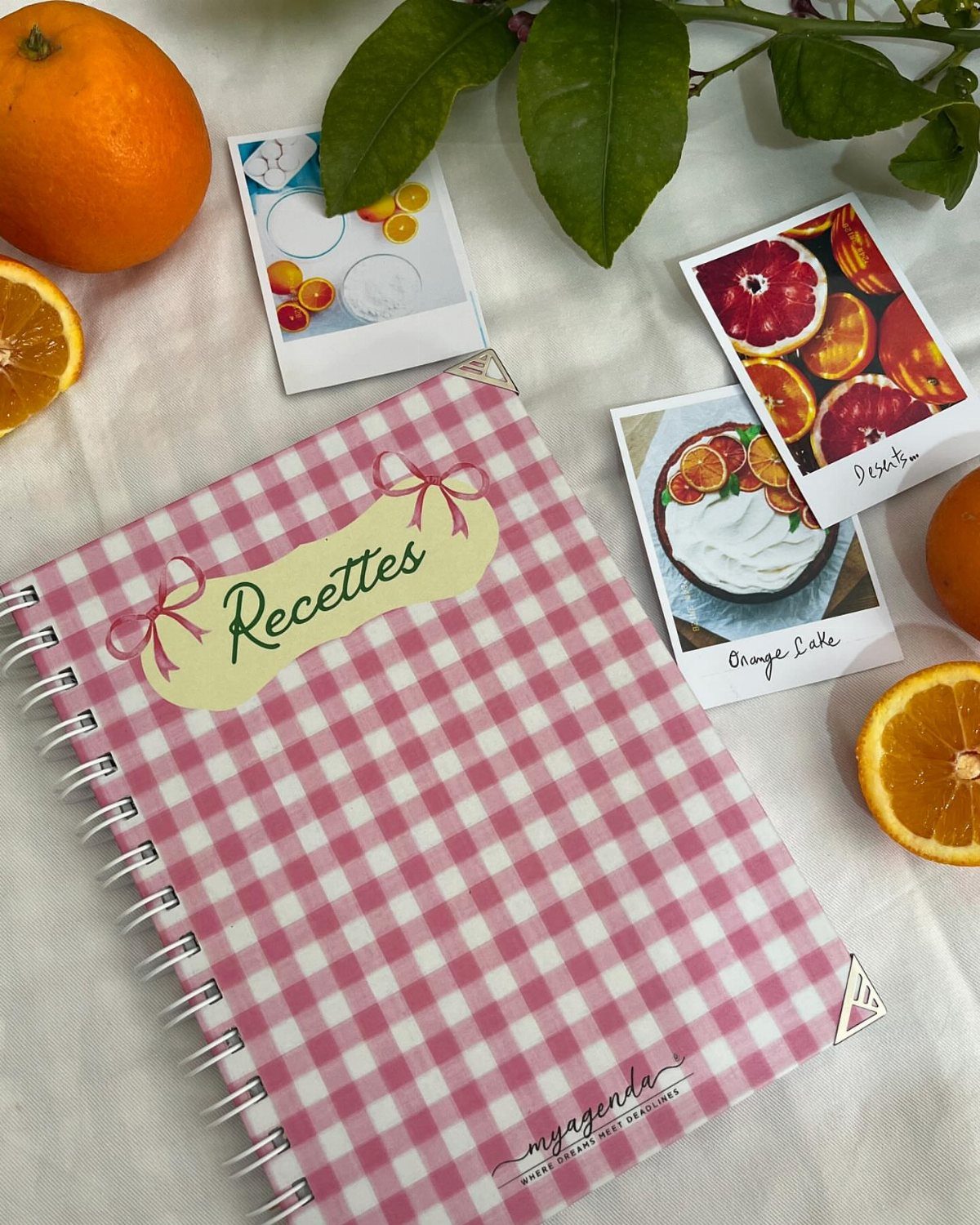 18 Mothers Day Gifts to Make: Easy Handmade Ideas for Mom 13 Pink gingham recipe notebook surrounded by orange slices and food polaroids on white cloth.