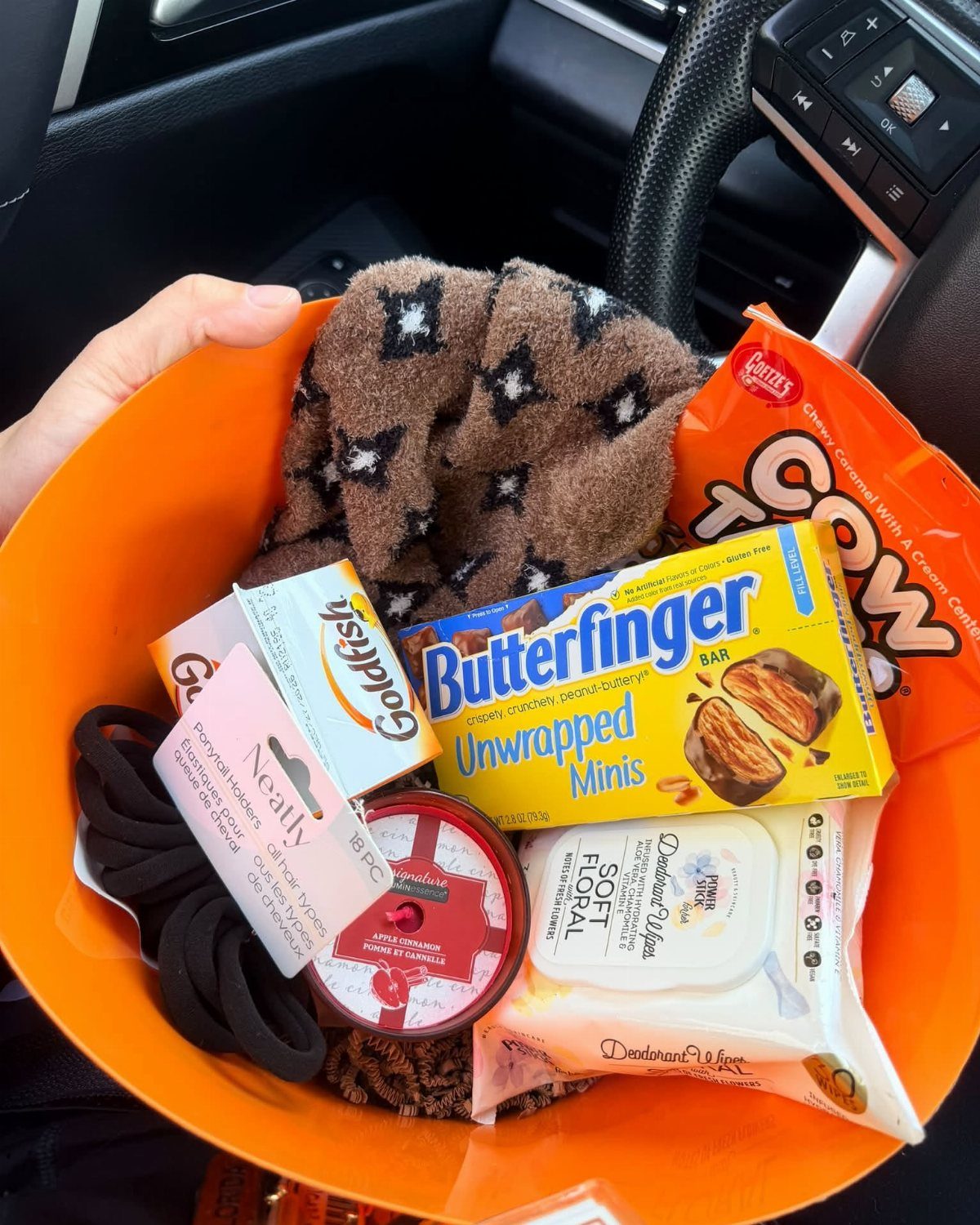 Orange bowl filled with orange-themed snacks, a brown cloth, and personal care items.