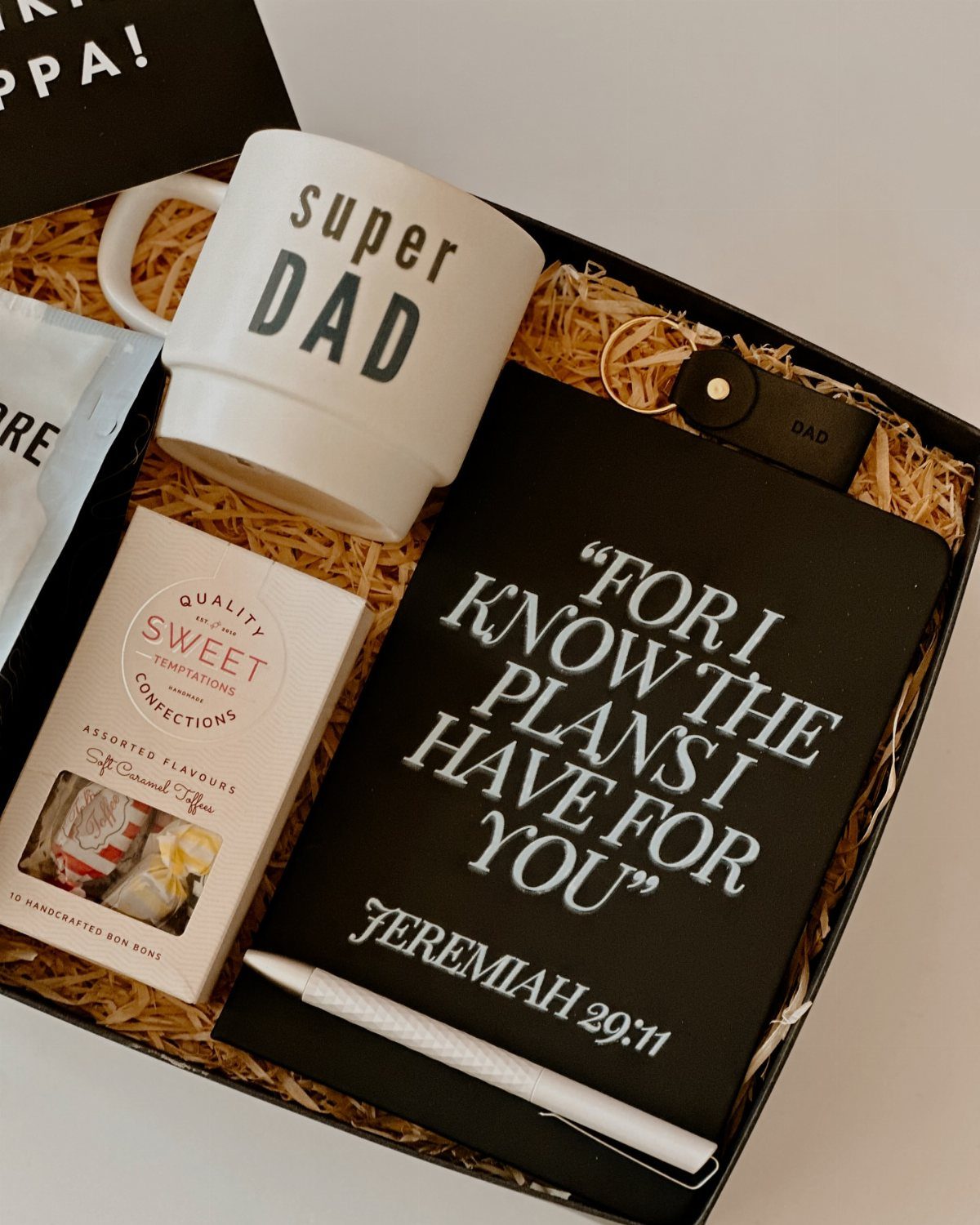 Gift box for dad containing a Super Dad mug, notebook, and keychain.