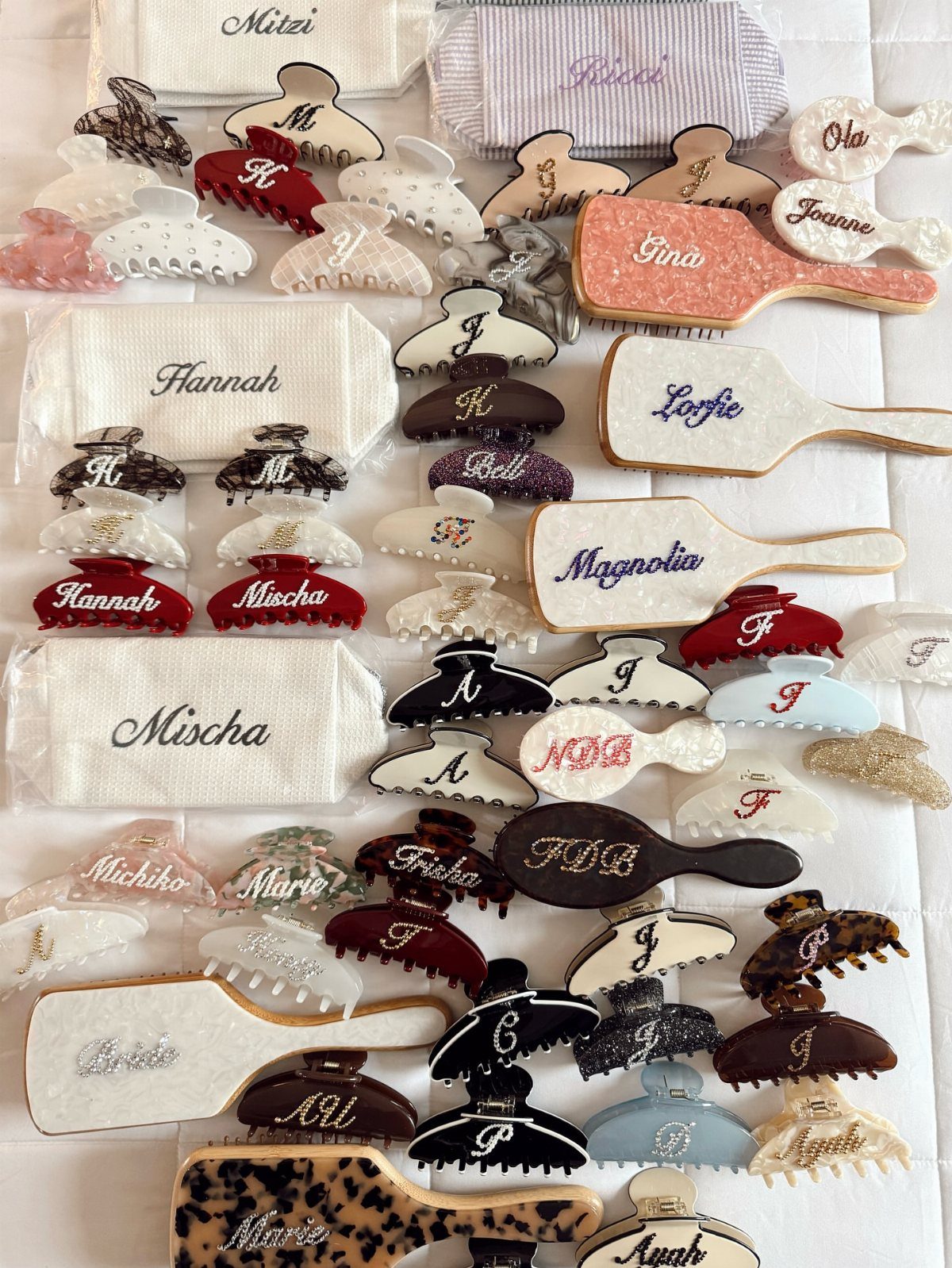 17 Personalized Gifts for Friends: Ideas for Every Budget 16 Personalized hair accessories with names, including claw clips and brushes, on white fabric.