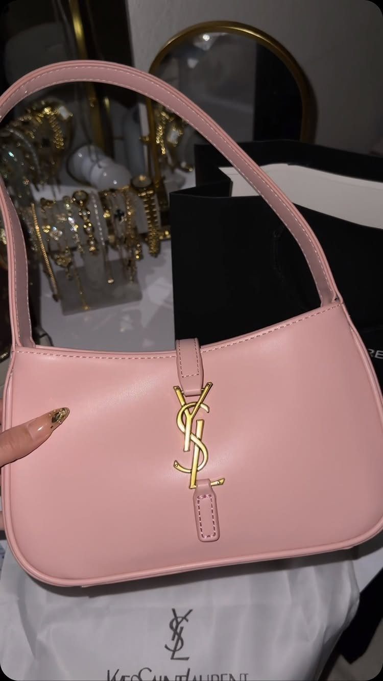24 Pink Christmas Gift Ideas from Cozy to Glam 11 Pink leather YSL handbag with gold logo resting on a white branded dust bag.