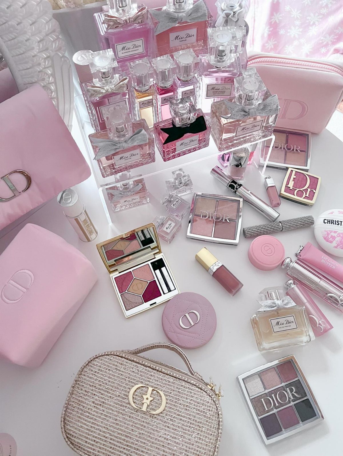 24 Pink Christmas Gift Ideas from Cozy to Glam 17 Pink Dior perfumes, makeup palettes, and accessories arranged as a luxury gift set.