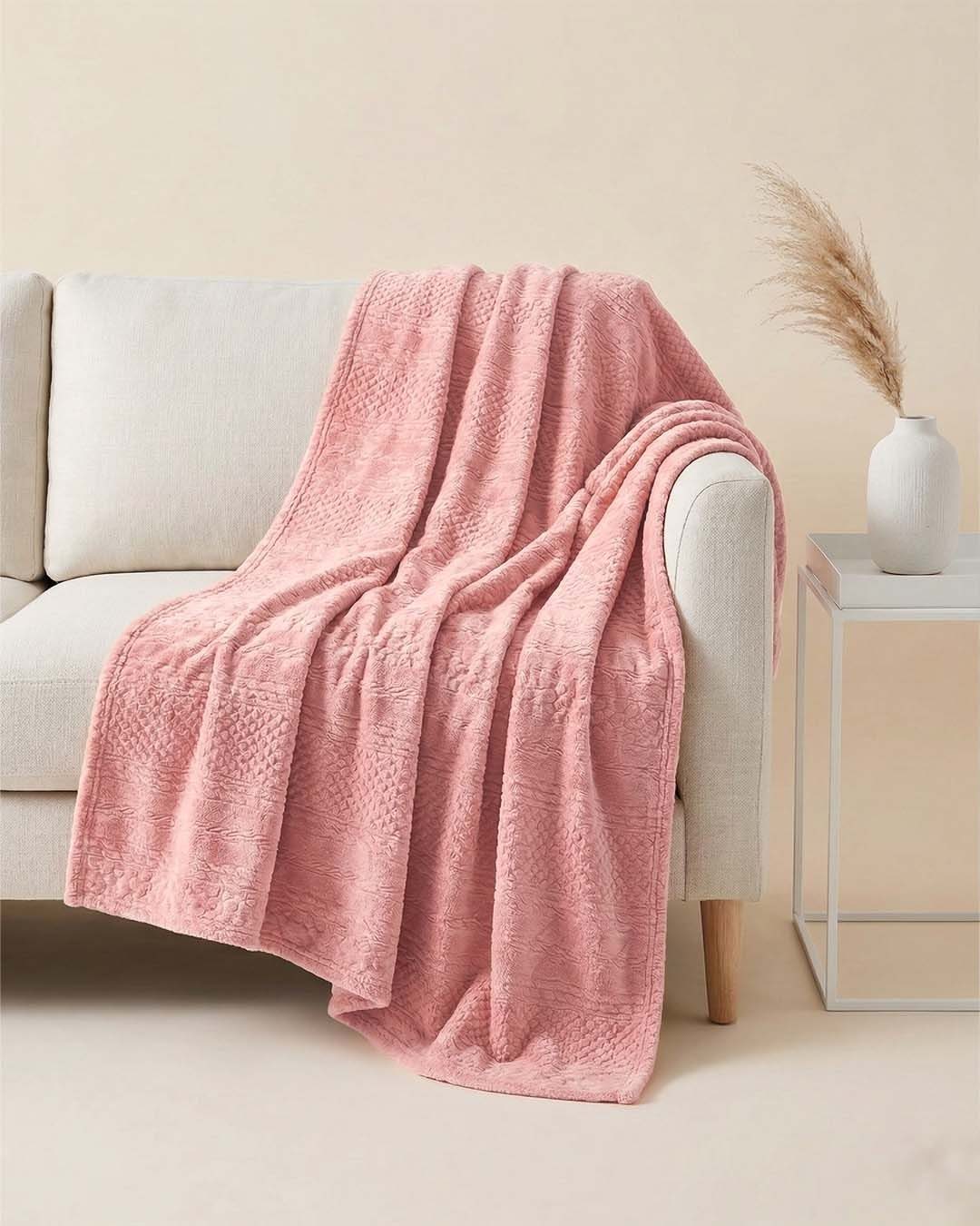 24 Pink Christmas Gift Ideas from Cozy to Glam 5 Pink fleece blanket draped over a beige sofa next to a white side table