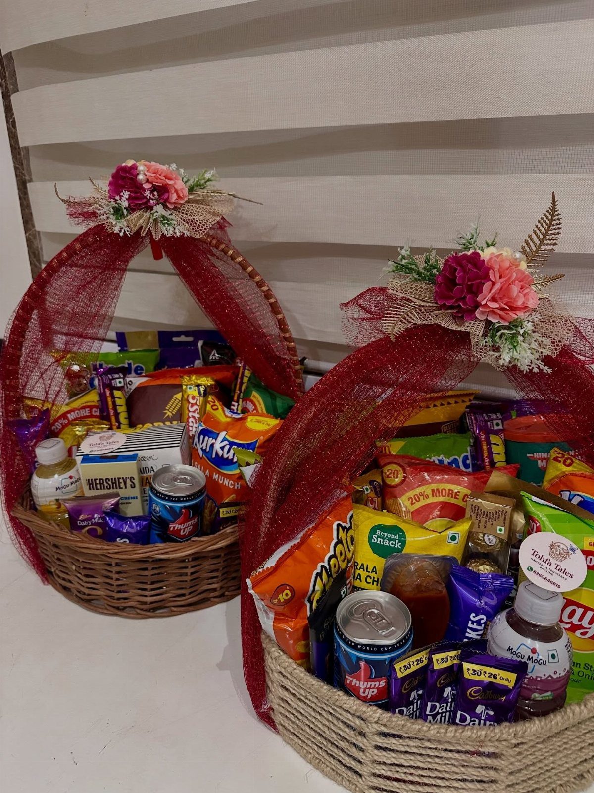 8 Senior Citizen Gift Basket Ideas for Grandparents 5 Two wicker gift baskets filled with snacks and decorated with red mesh and flowers.