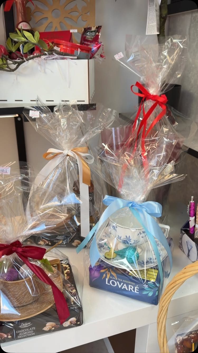 8 Senior Citizen Gift Basket Ideas for Grandparents 2 Wrapped gift baskets with ribbons containing treats and a teacup on a shelf