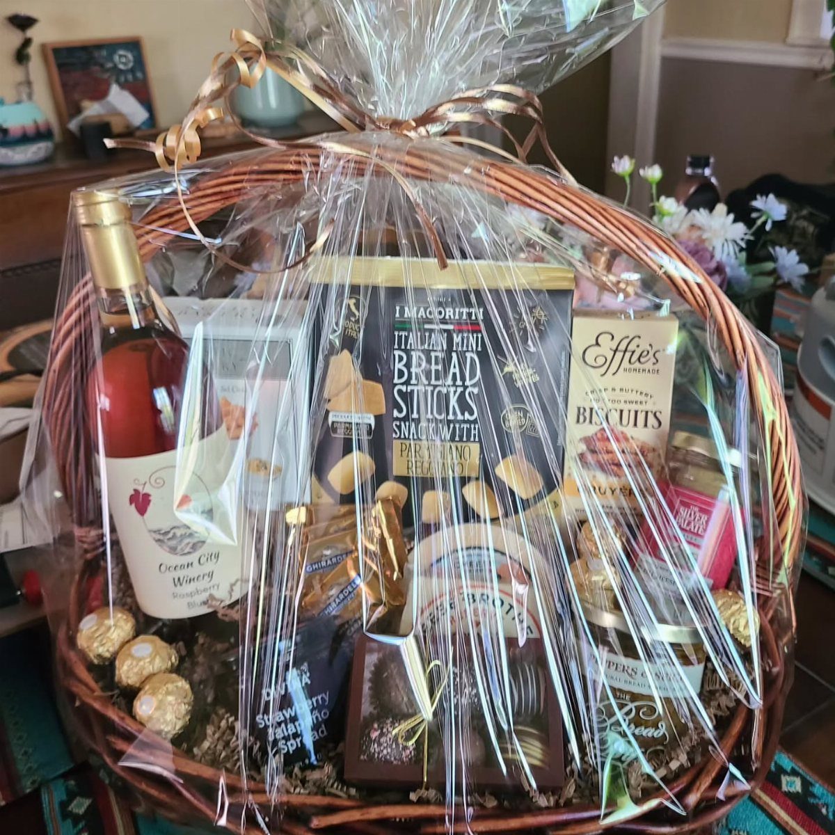 8 Senior Citizen Gift Basket Ideas for Grandparents 1 Wicker gift basket containing a bottle of rosé wine and various gourmet snacks.
