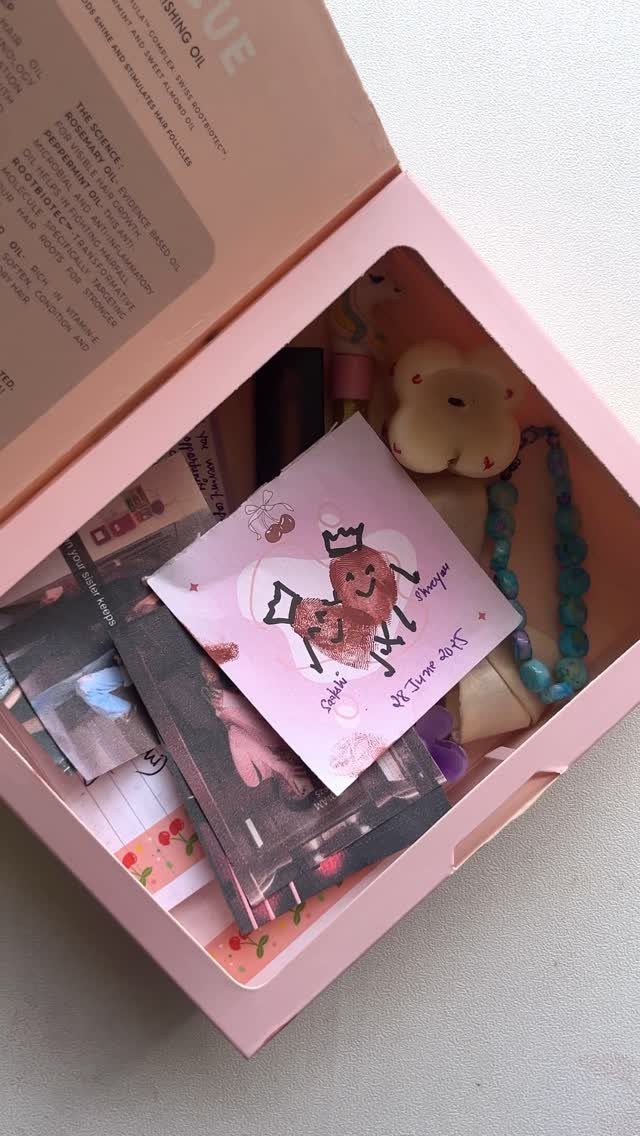 Pink memory box filled with hand-drawn cards, photographs, and a beaded necklace.