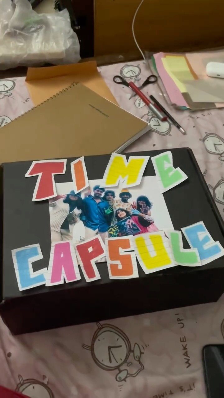Black time capsule box decorated with colorful letters and a group photograph.