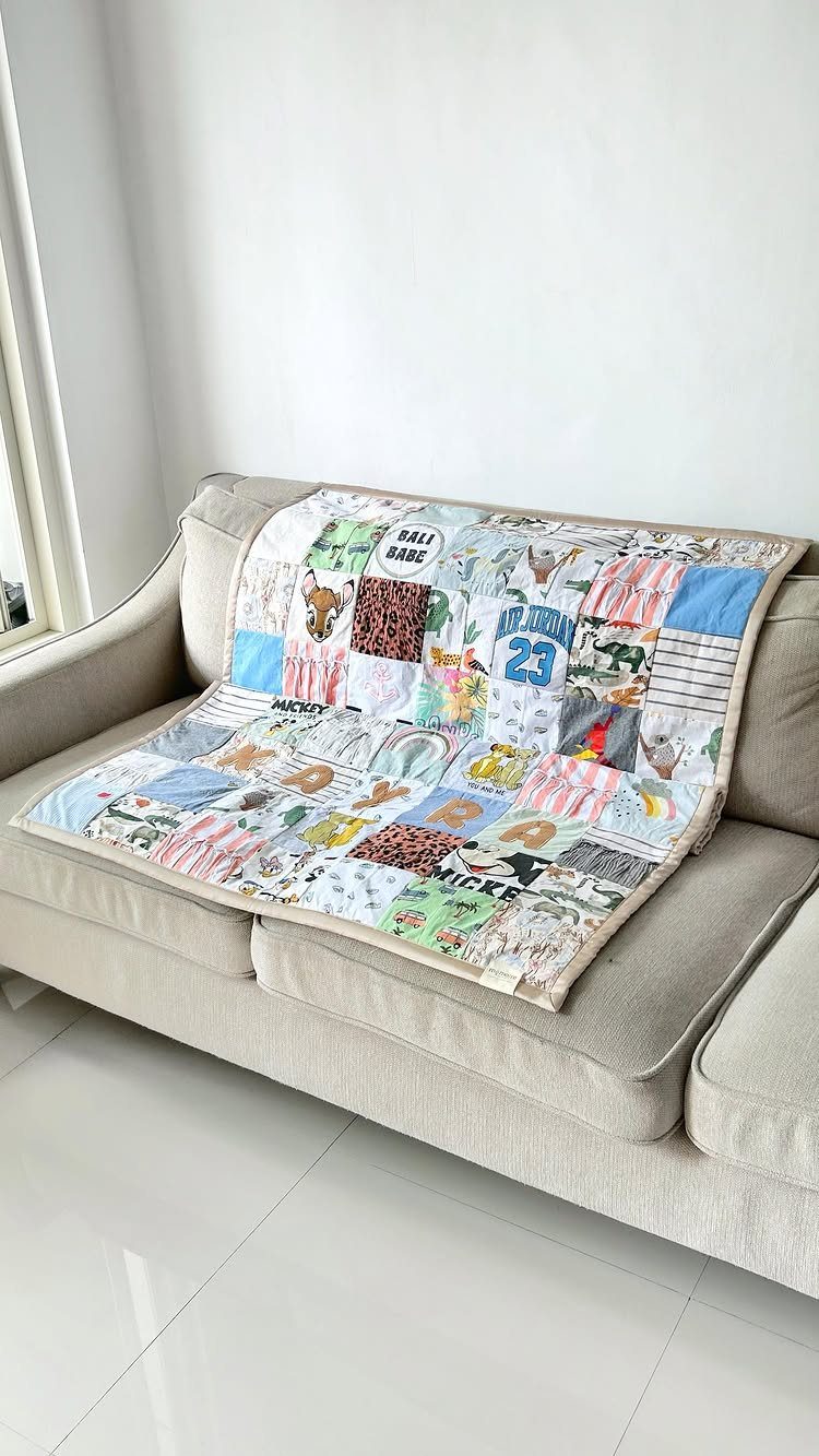 Colorful patchwork quilt with animal patterns draped over a beige fabric sofa.