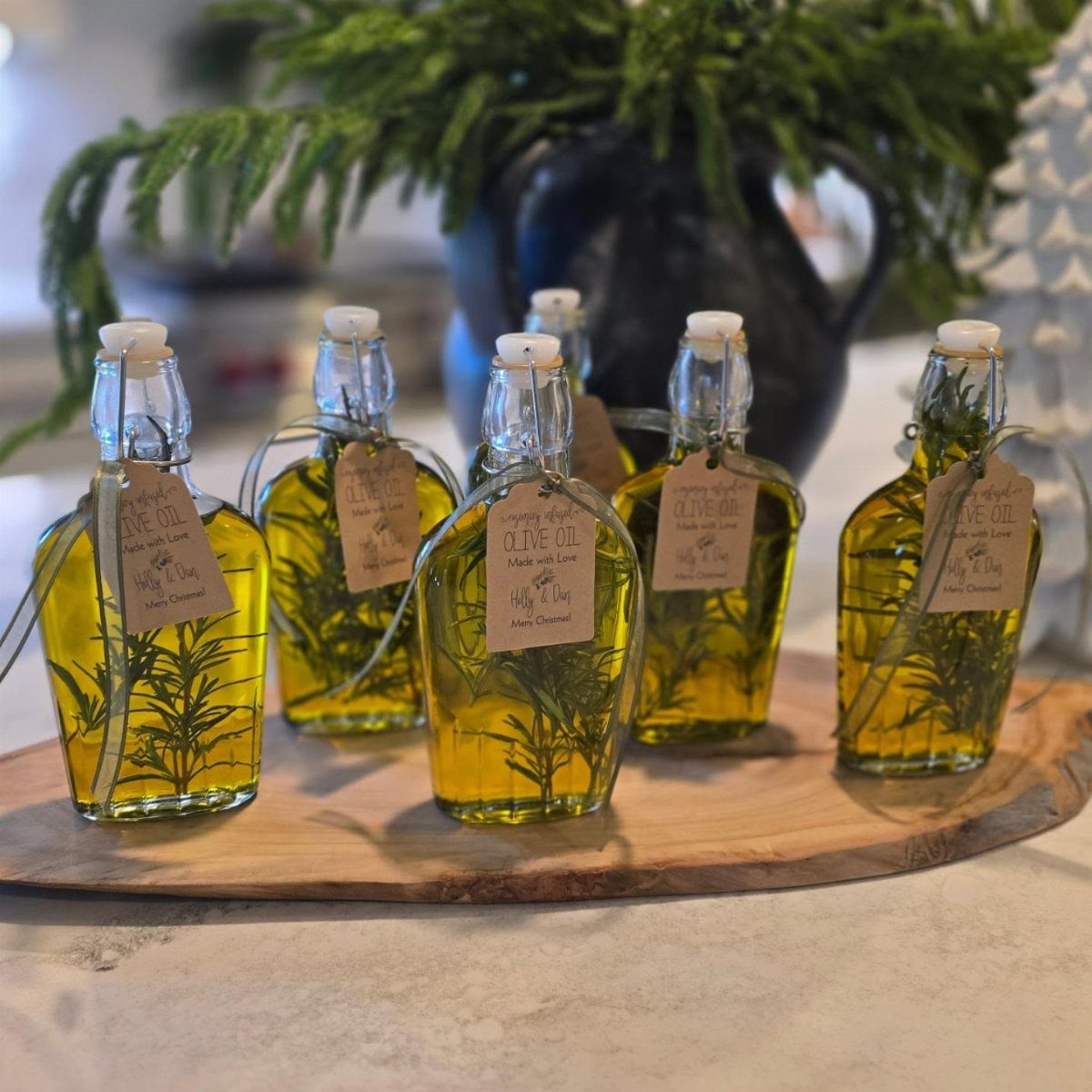 Small glass bottles of rosemary infused olive oil with tags on a wooden board