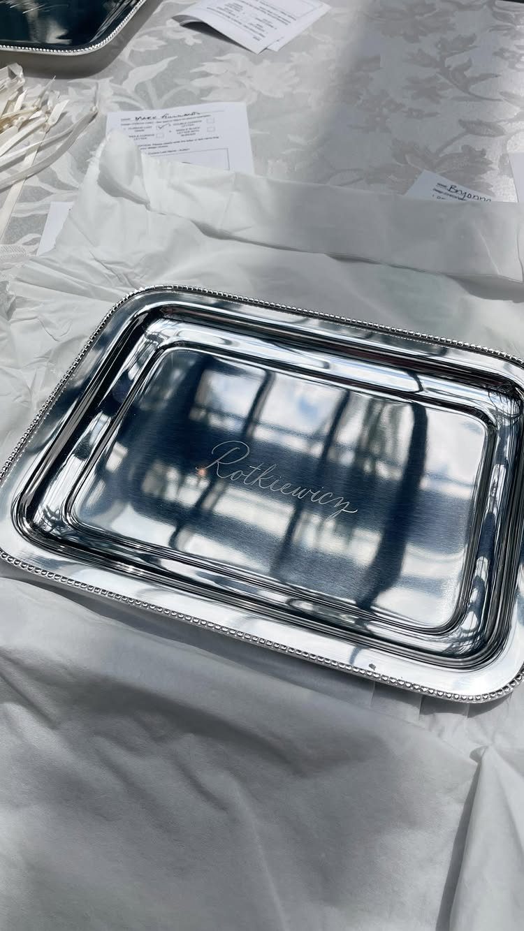 Silver rectangular serving tray with engraved cursive name on white tissue paper