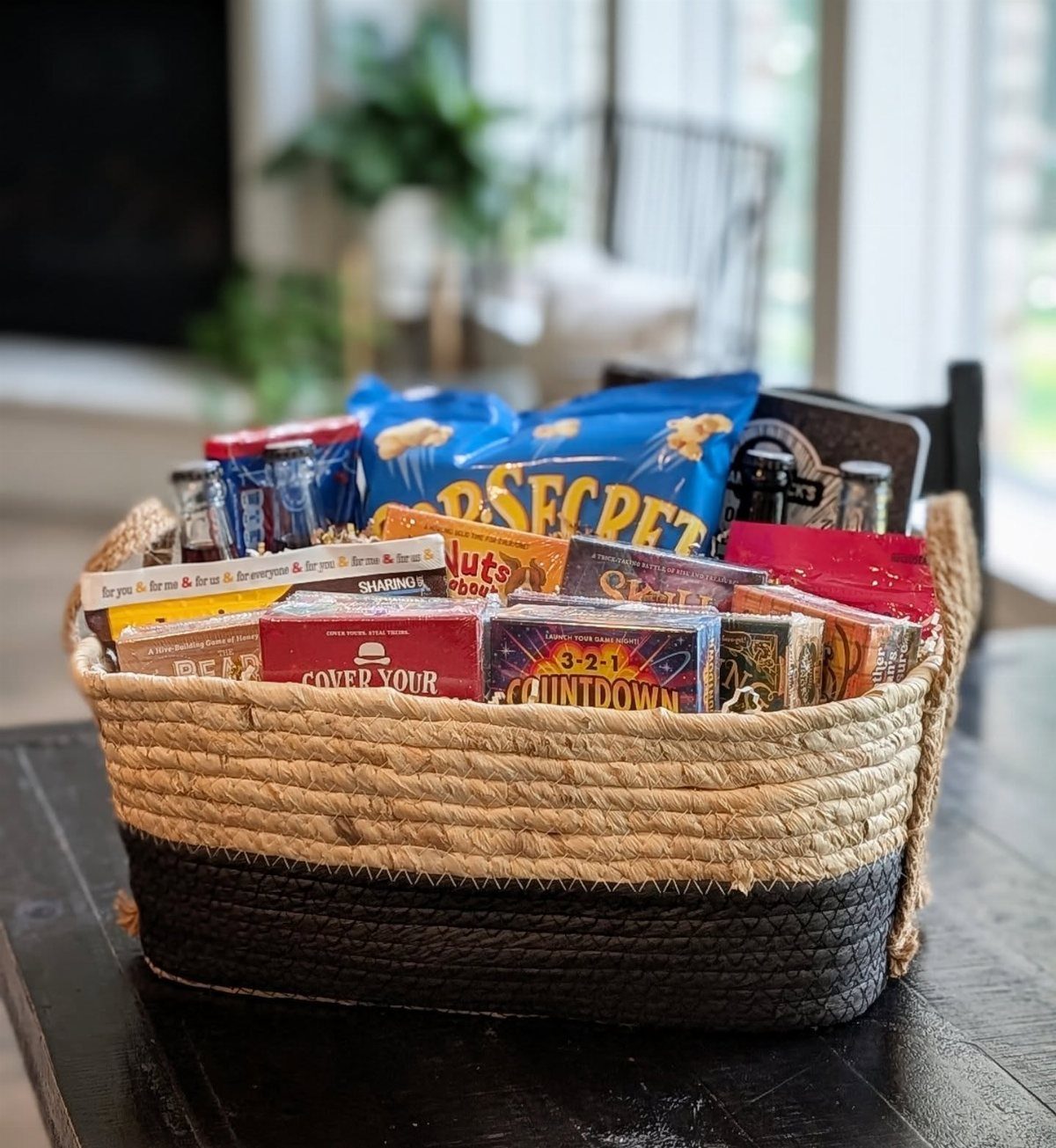 12 Silent Auction Gift Basket Ideas for Any Fundraiser 4 Woven basket filled with various boxed card games and blue snack bags.