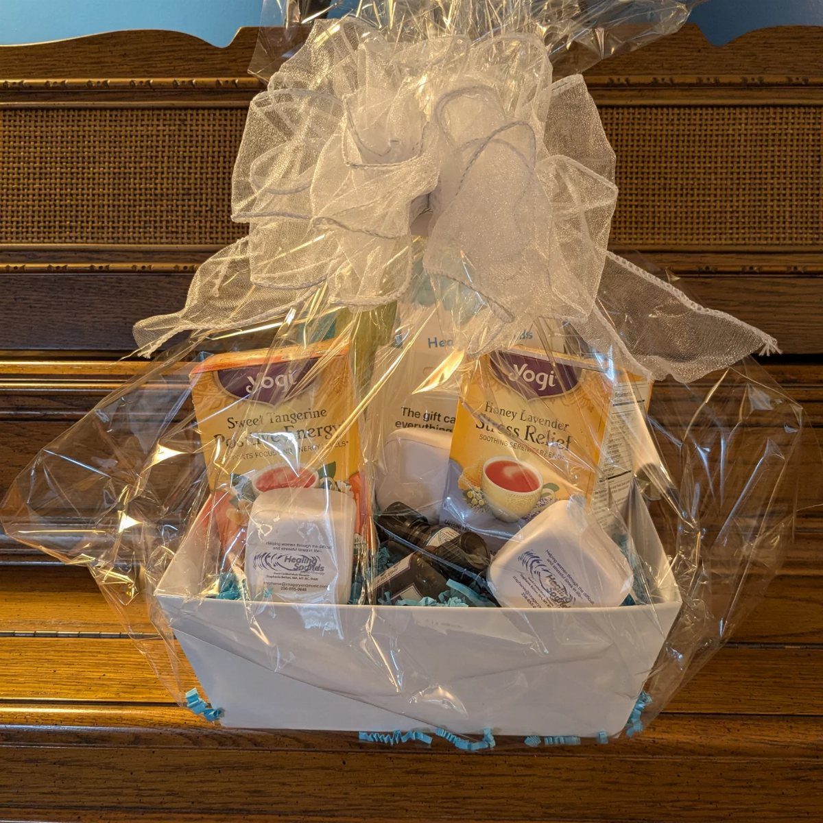 12 Silent Auction Gift Basket Ideas for Any Fundraiser 8 White gift basket with tea and soaps wrapped in cellophane with a bow