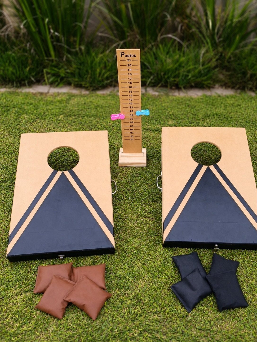 8 Small Gifts for Family That Everyone Will Enjoy 4 Cornhole boards with bean bags and a wooden scoreboard on a green lawn.