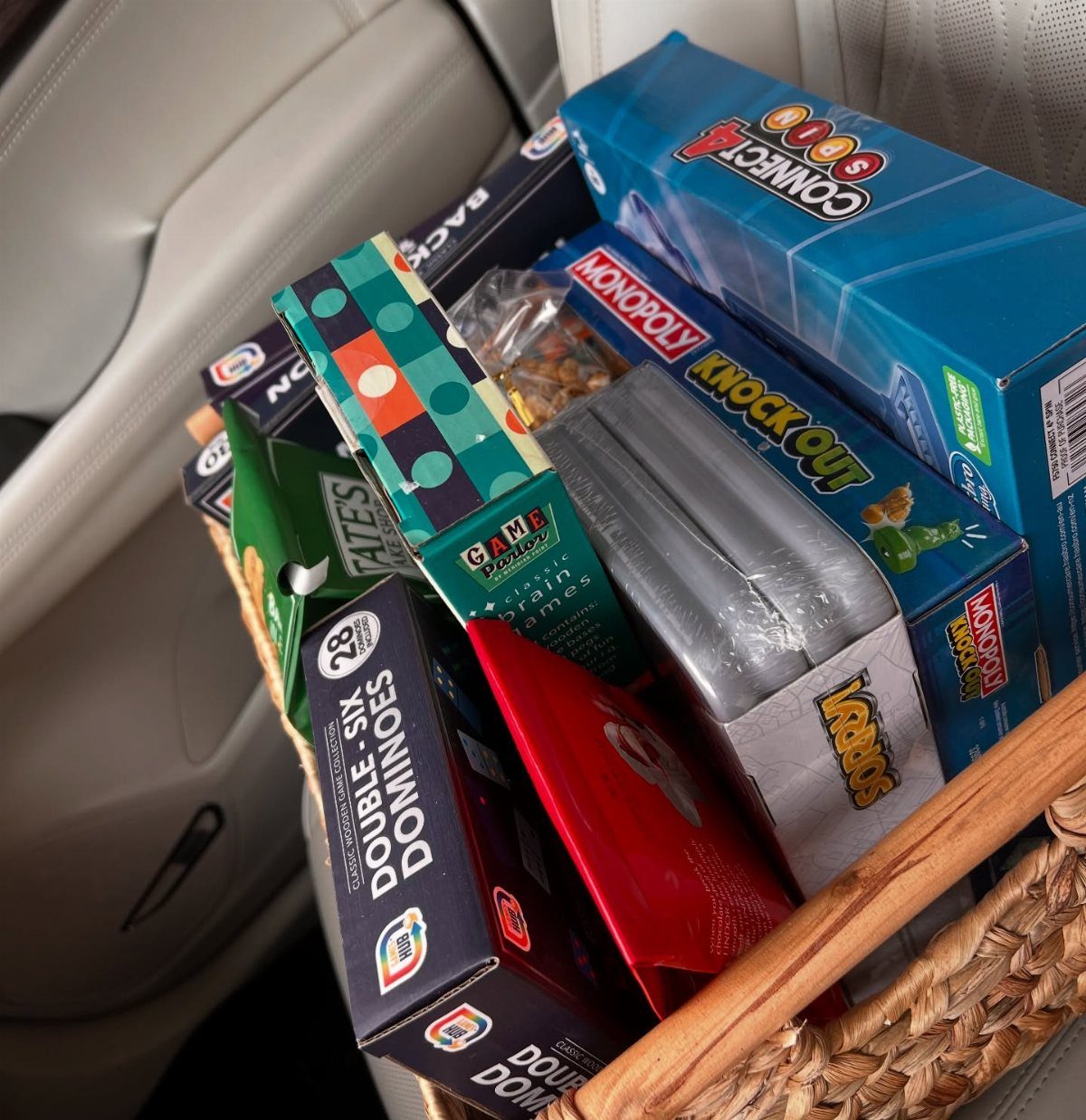 8 Small Gifts for Family That Everyone Will Enjoy 3 Wicker basket filled with board games and snacks on a white car seat
