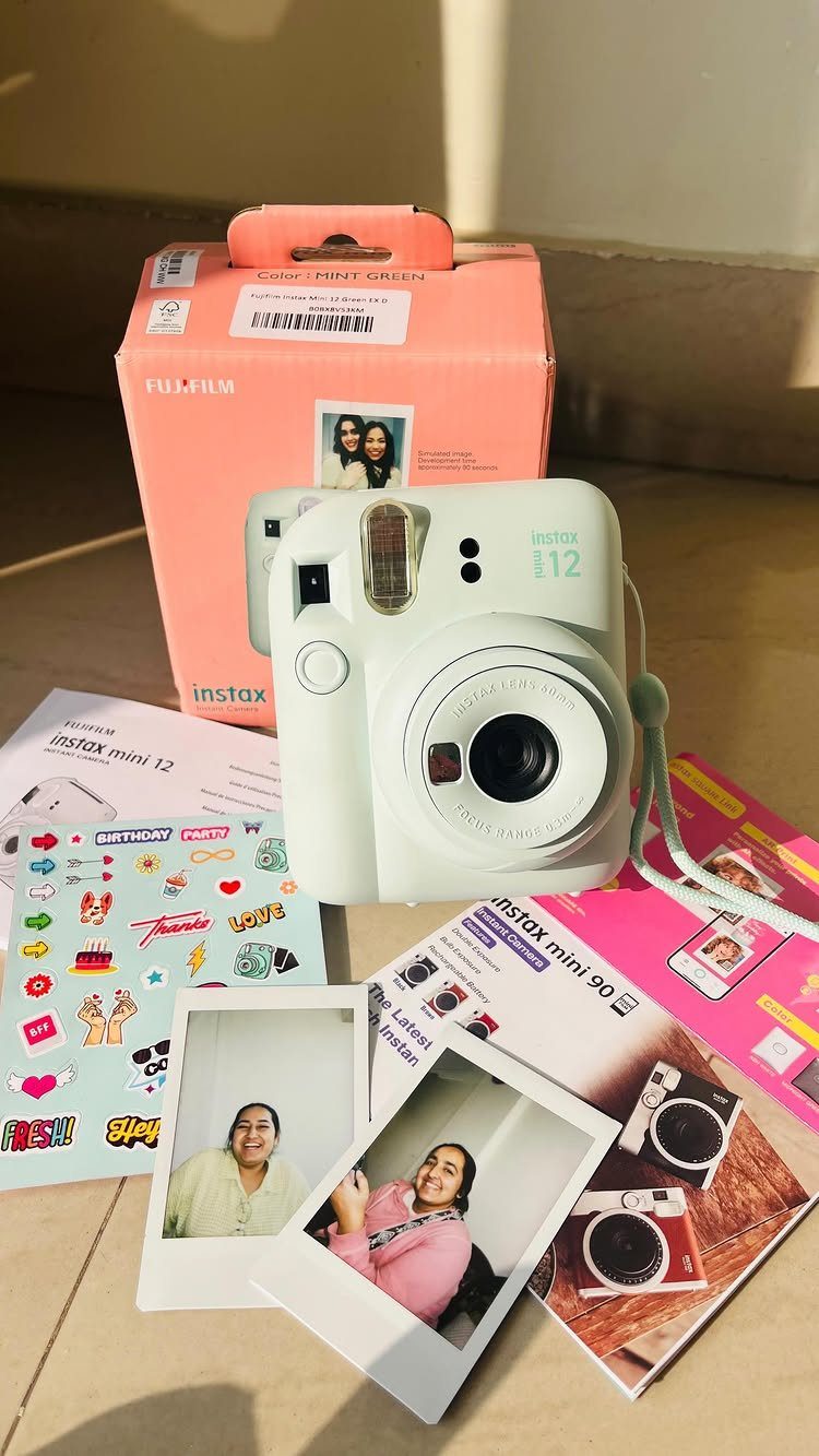 8 Small Gifts for Family That Everyone Will Enjoy 2 Light blue instant camera with pink box and printed photos on wooden table