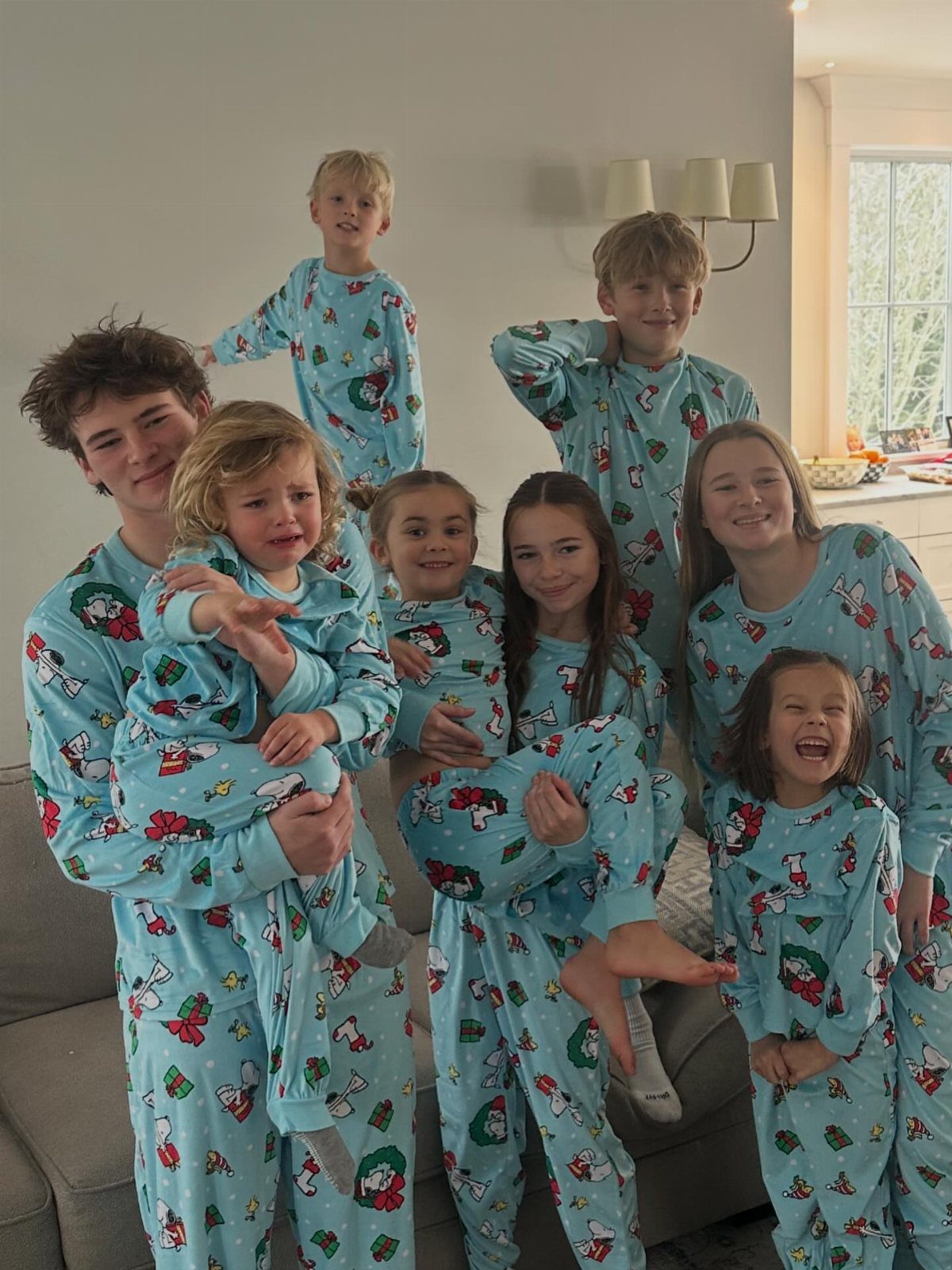8 Small Gifts for Family That Everyone Will Enjoy 1 Family of eight wearing matching light blue holiday pajamas posing in a living room.