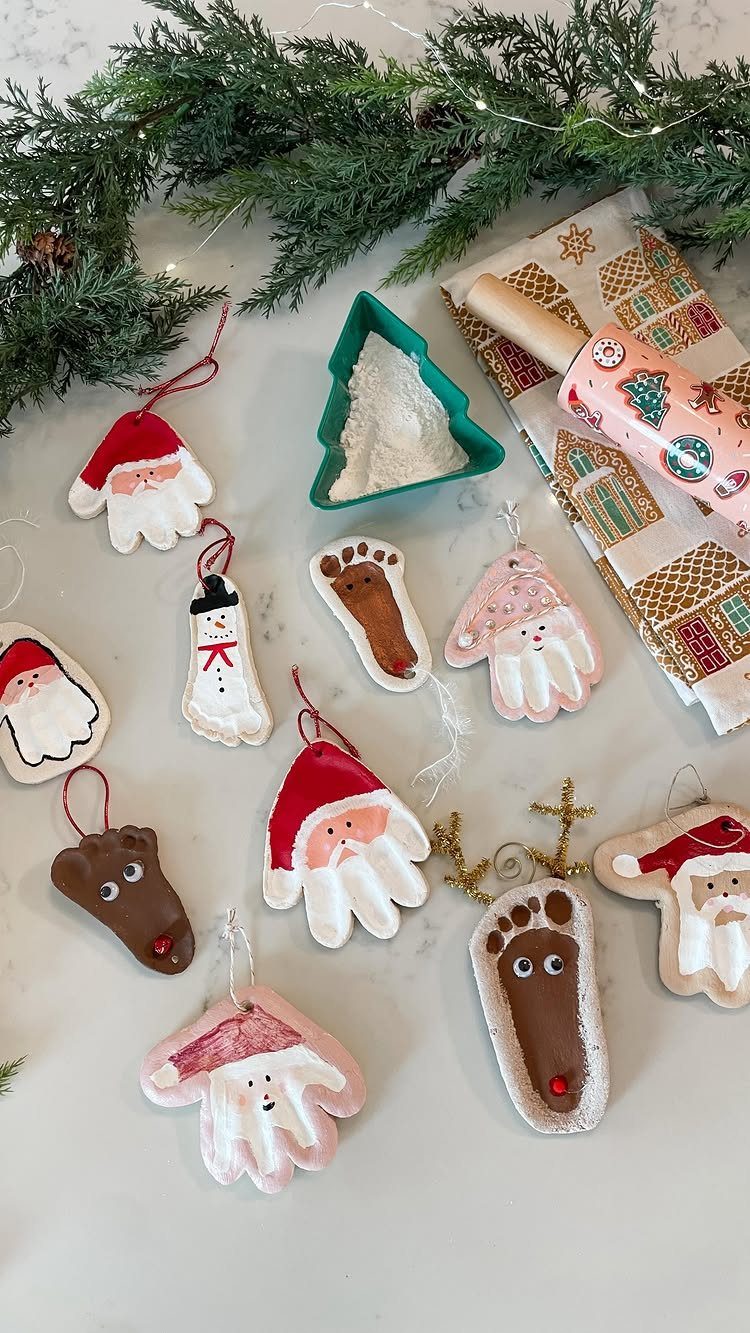 Handprint and footprint salt dough ornaments painted as Christmas characters on white surface