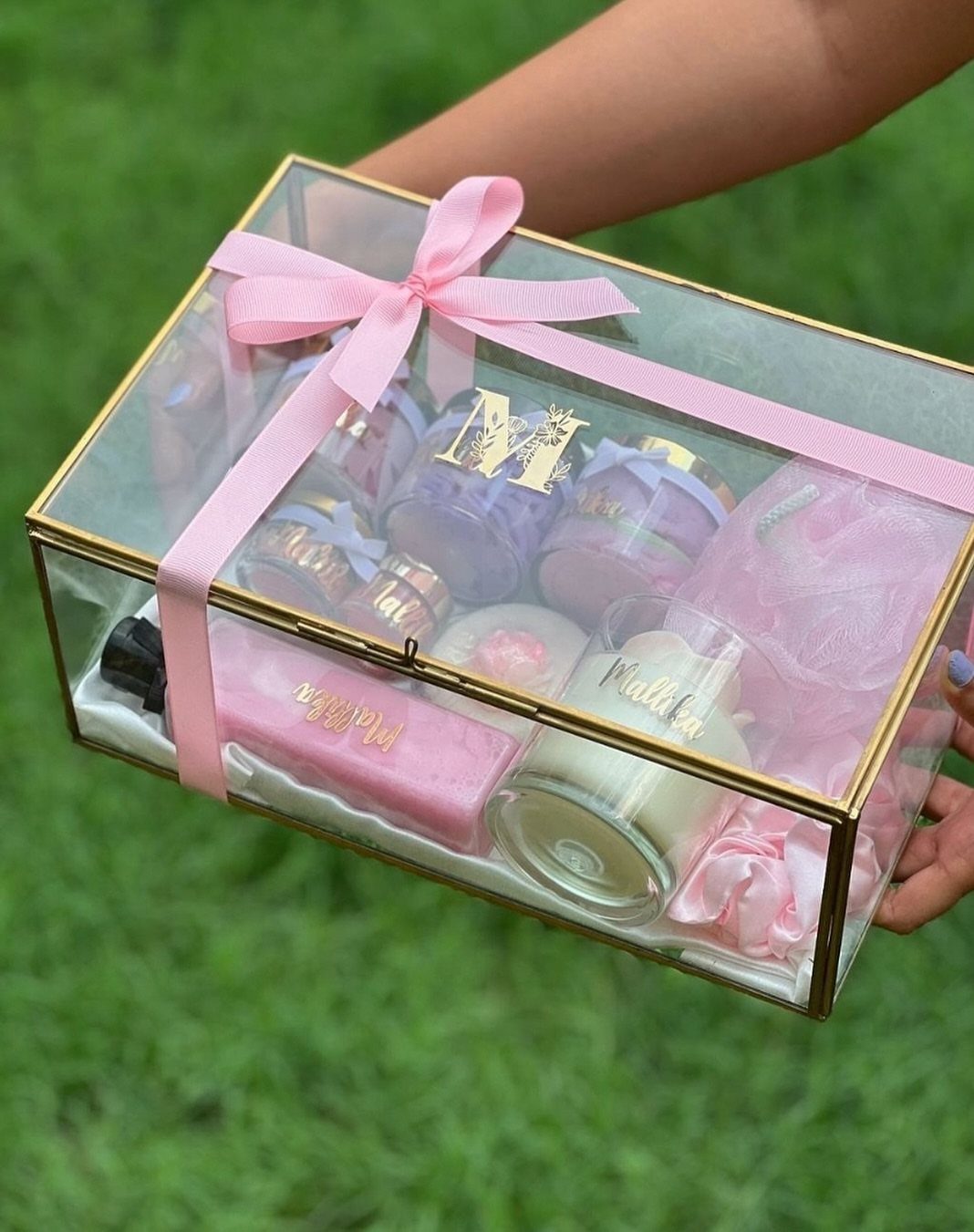 11 Spa Day Gift Basket Ideas for Relaxing at Home 4 Gold-rimmed glass gift box with pink ribbon containing spa products and candles.