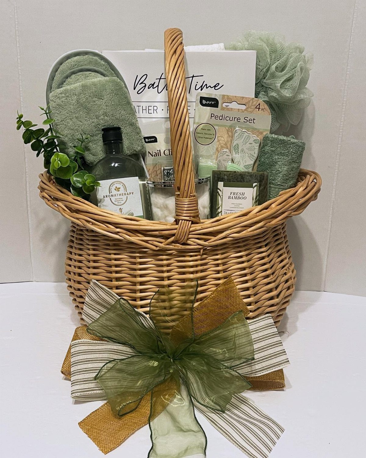 11 Spa Day Gift Basket Ideas for Relaxing at Home 9 Wicker gift basket filled with green spa products and a large decorative bow.