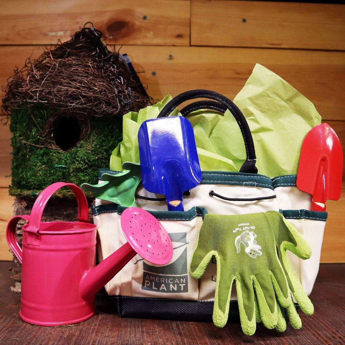 Gardening gift set with a tote bag, trowels, gloves, and pink watering can.