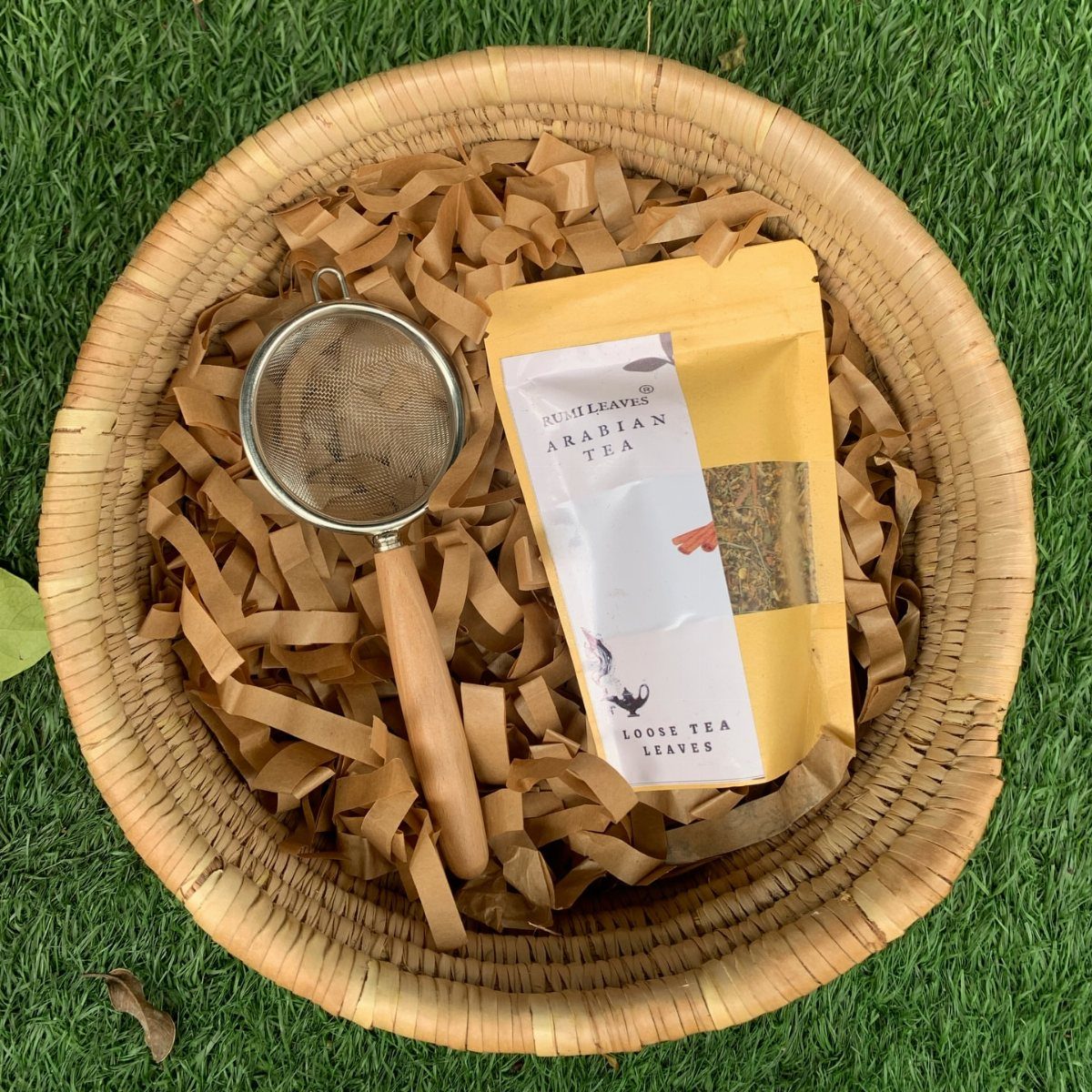 Tea gift basket with loose tea leaves and a strainer on green grass