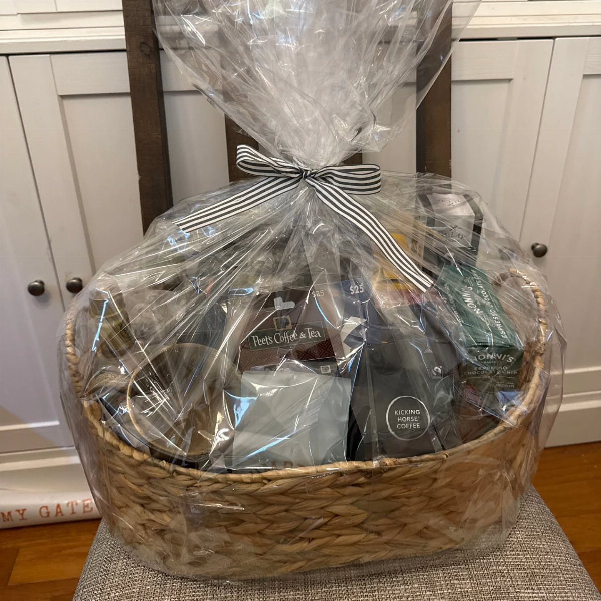Woven gift basket wrapped in cellophane with a striped bow containing tea products.