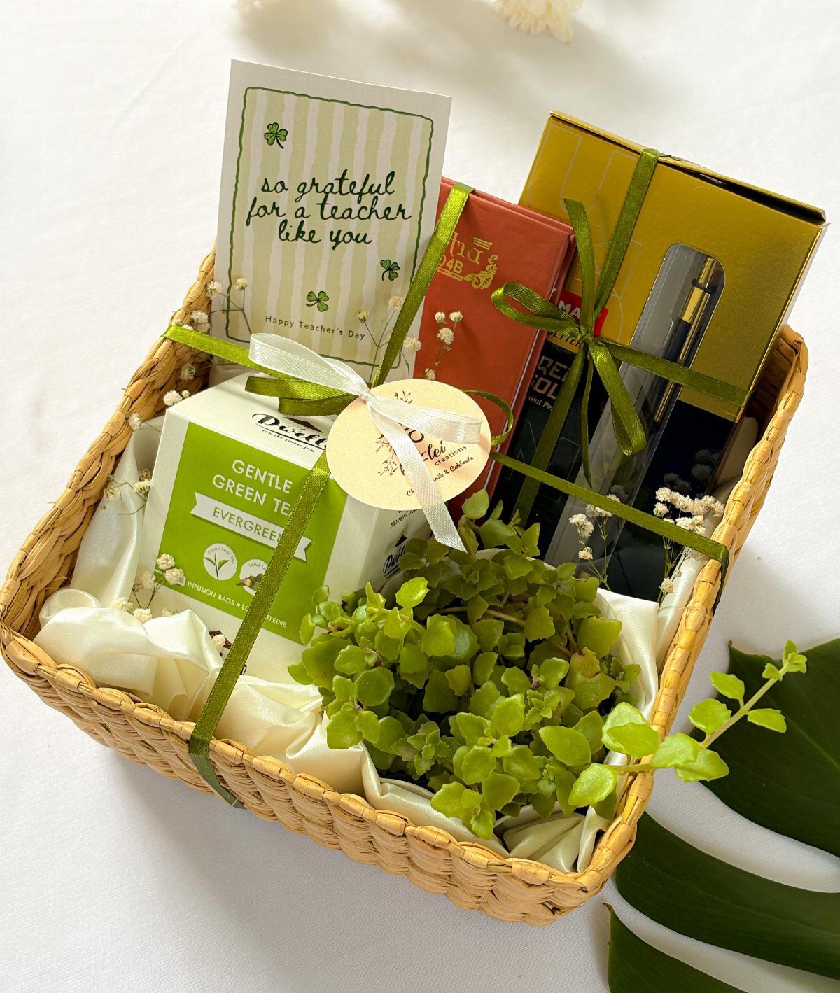 Woven gift basket with green tea, small plant, and a teacher appreciation card.