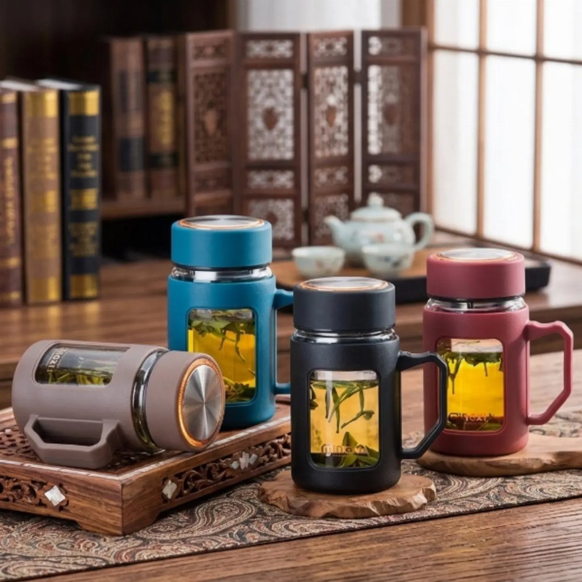 Four colorful tea infuser mugs with visible tea leaves on a wooden table.