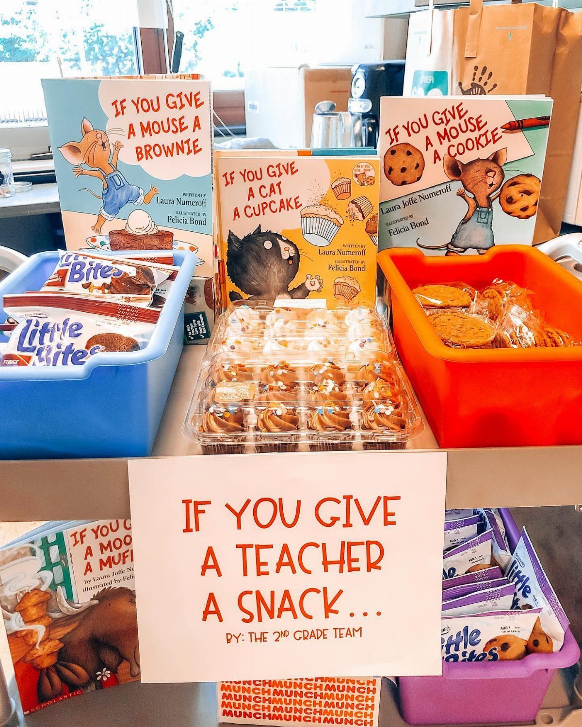 8 Teacher Gifts They Actually Want, From Notes to Totes 5 Snack bins and children's books arranged with a sign for teacher appreciation.