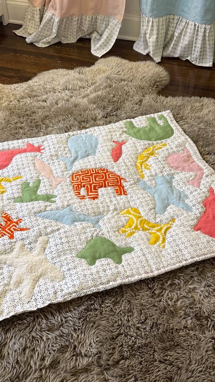 15 Unusual Sewing Gifts to Make for Friends and Family 14 Quilted baby blanket with colorful animal appliques on a shaggy brown rug