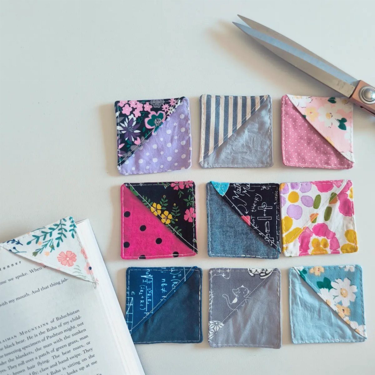 15 Unusual Sewing Gifts to Make for Friends and Family 9 Fabric corner bookmarks in colorful patterns arranged on a white surface with scissors.