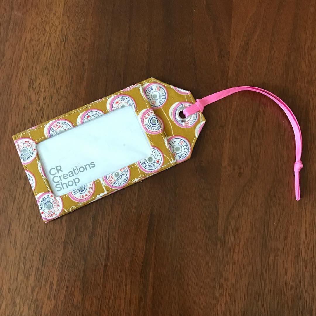15 Unusual Sewing Gifts to Make for Friends and Family 6 Fabric luggage tag with yellow patterned print and pink strap on wooden table