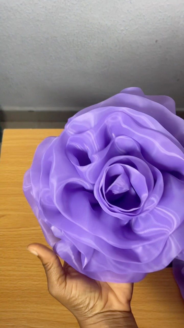 15 Unusual Sewing Gifts to Make for Friends and Family 12 Large purple fabric rose held by a hand over a wooden table
