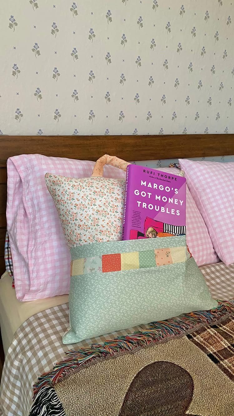 15 Unusual Sewing Gifts to Make for Friends and Family 5 Blue patterned pillow with a book pocket resting on a bed with pink pillows
