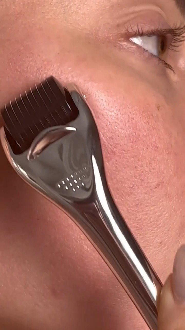 Facial dermaplaning tool being used on a person's cheek for skin exfoliation.