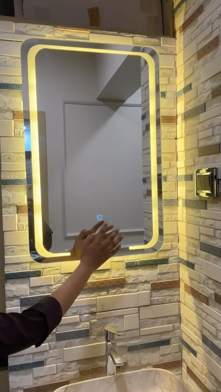 Rectangular LED vanity mirror with glowing yellow border on a tiled bathroom wall
