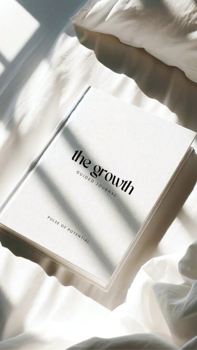White guided journal titled the growth resting on soft white bed sheets