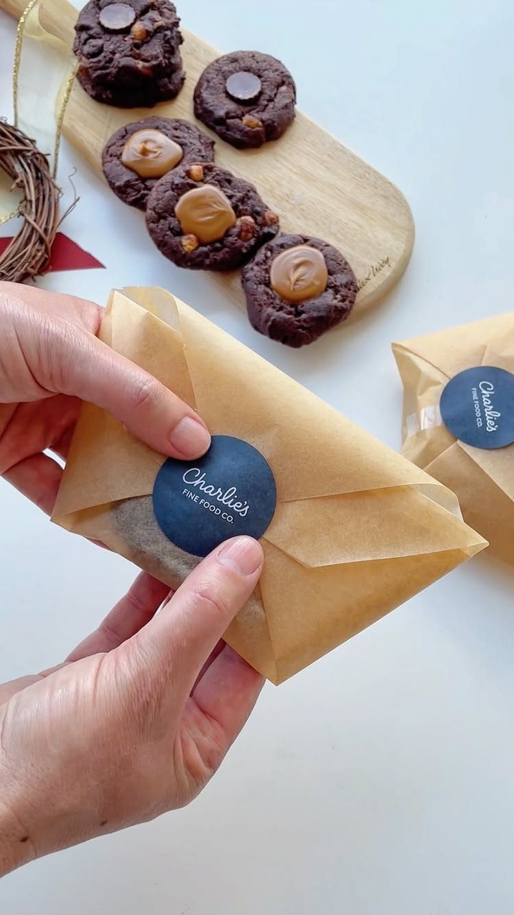 12 Useful Homemade Christmas Gifts People Will Use 1 Hands sealing a brown paper package of cookies with a blue brand sticker.