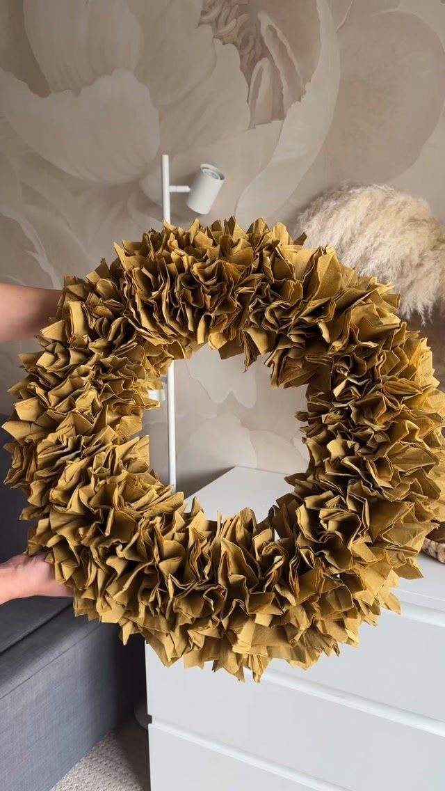 12 Useful Homemade Christmas Gifts People Will Use 10 Gold paper wreath held by hands in front of a white dresser.