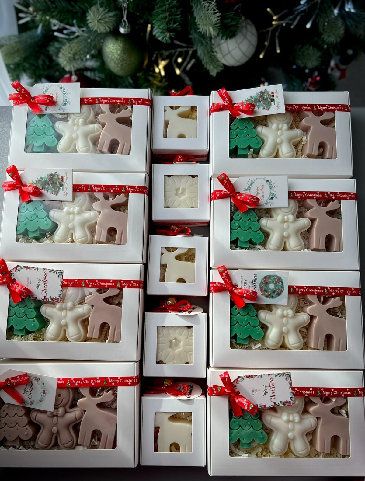 13 Warm and Cozy Gift Ideas for Winter Gifting 8 White gift boxes containing shaped Christmas candles in green, white, and brown colors.