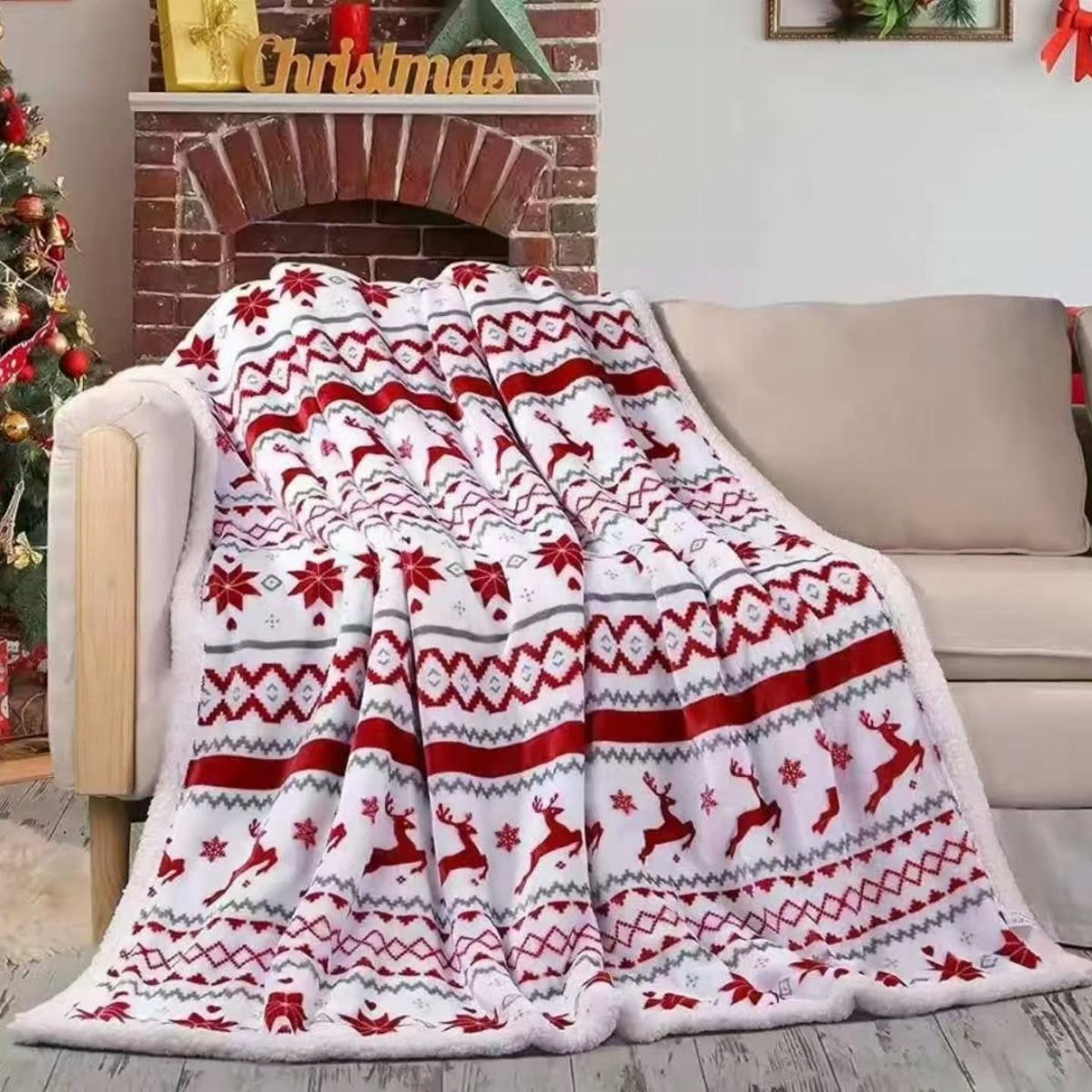 13 Warm and Cozy Gift Ideas for Winter Gifting 1 White fleece blanket with red reindeer patterns draped over a beige living room sofa.
