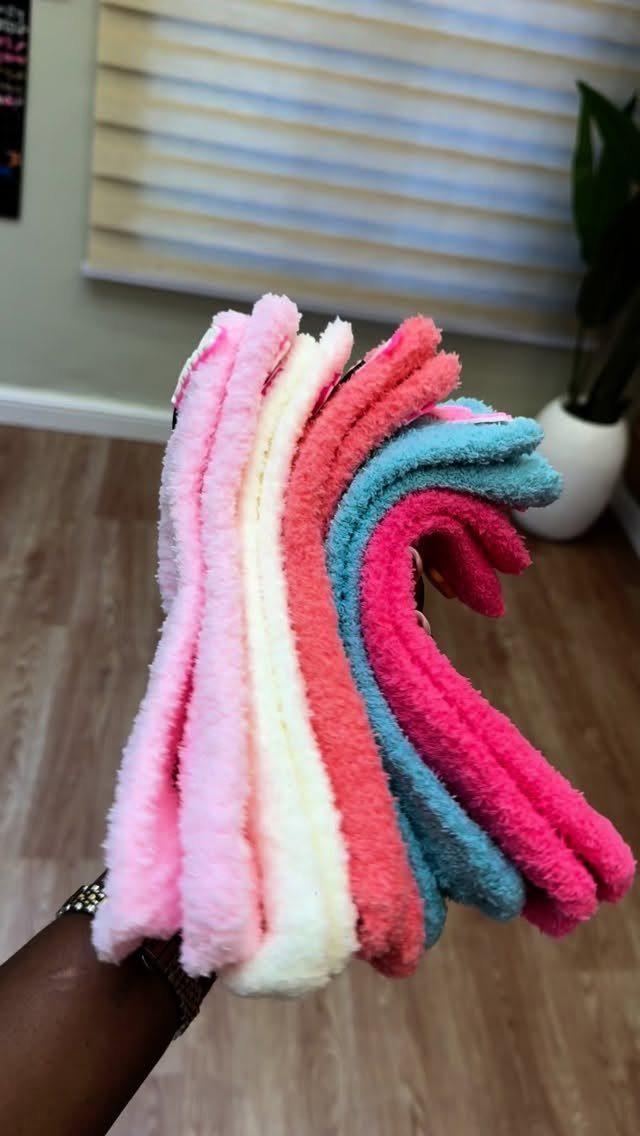 13 Warm and Cozy Gift Ideas for Winter Gifting 4 Stack of colorful fuzzy socks in pink, cream, coral, and blue held by hand.