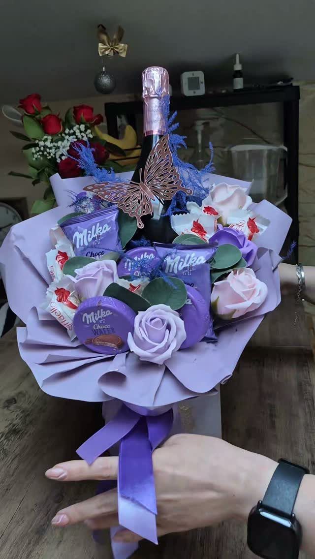 Sparkling wine and Milka chocolate bouquet with purple roses and butterfly decoration.