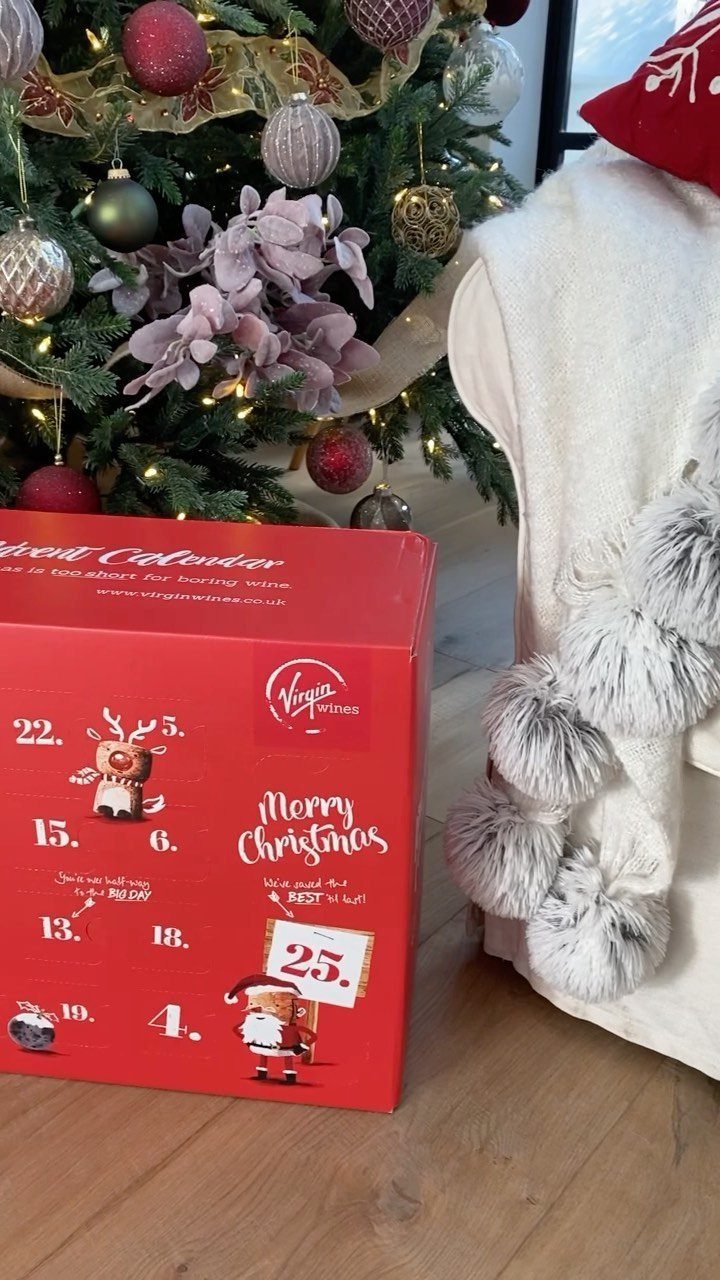 Red wine advent calendar box placed on wooden floor near decorated Christmas tree