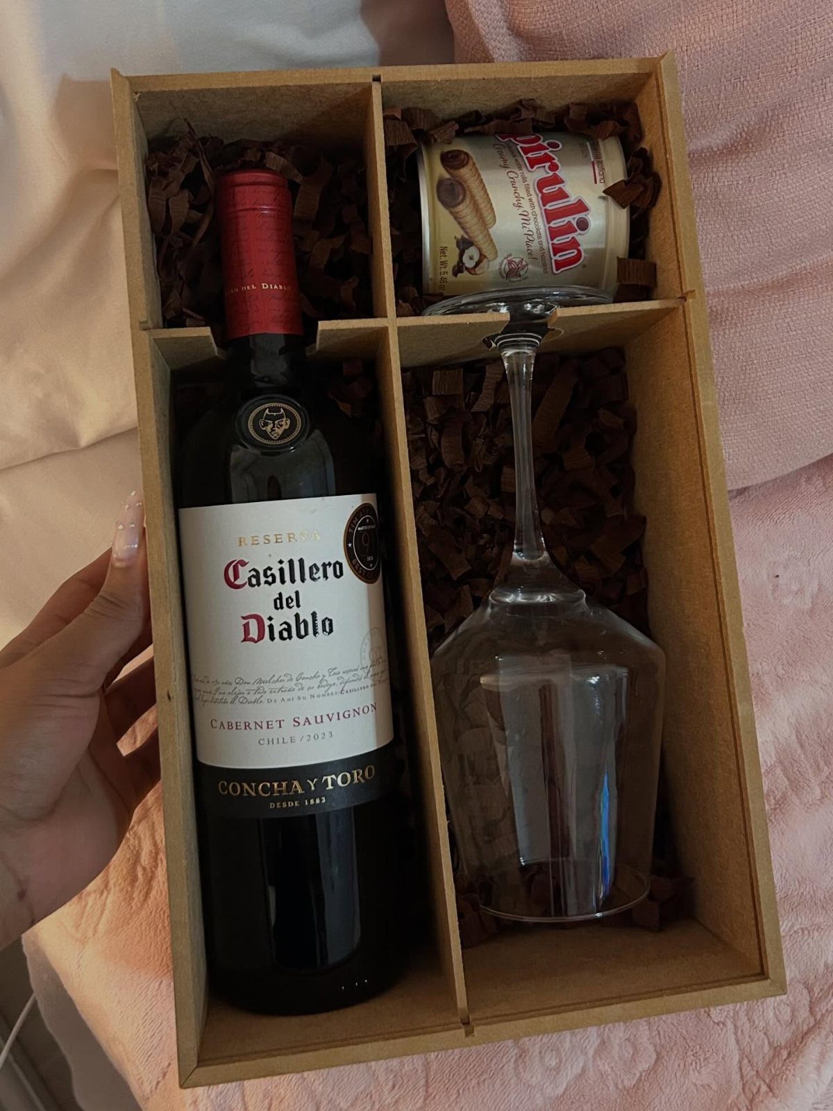 Red wine bottle, wine glass, and cookie tin in a cardboard gift box