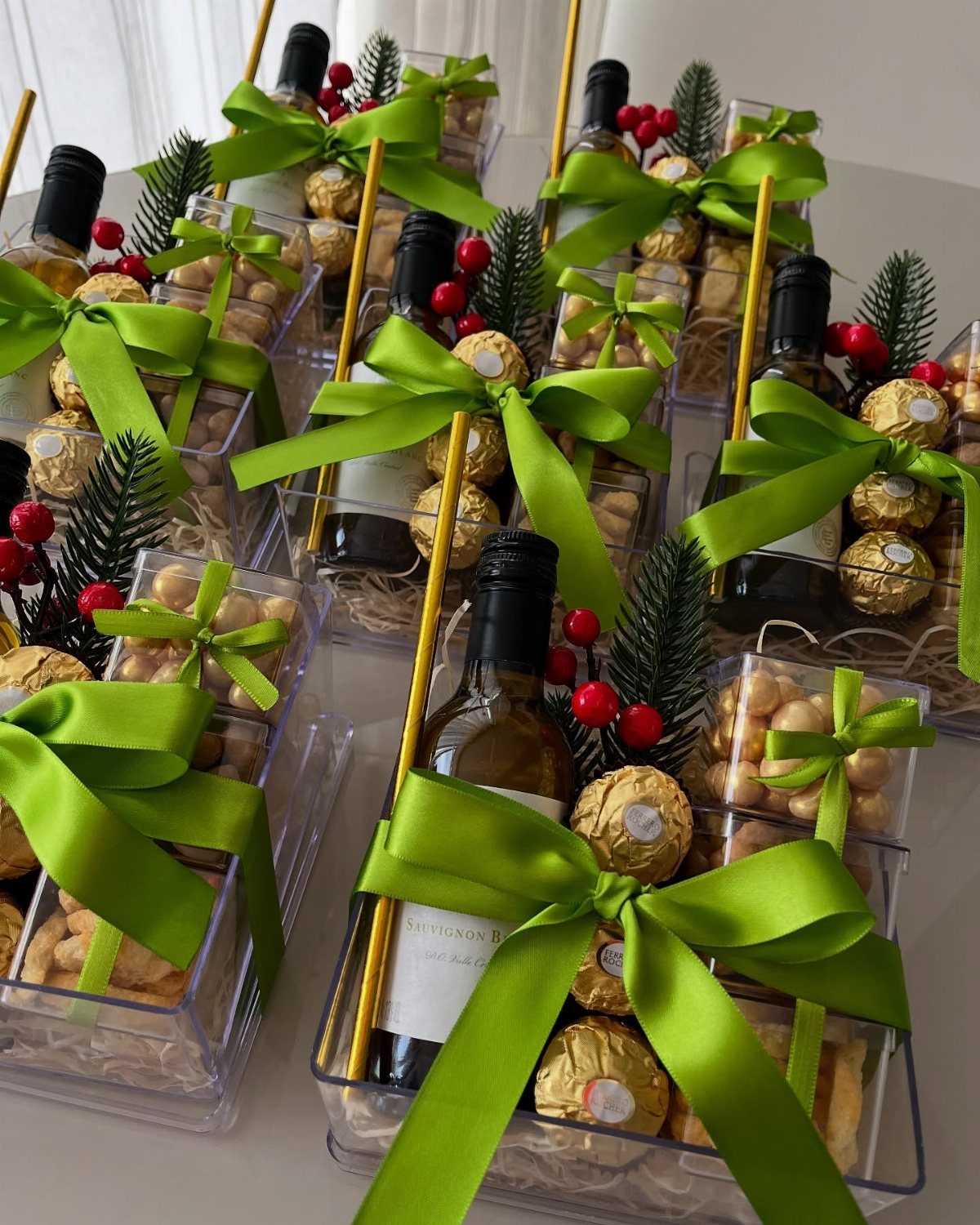 Wine gift boxes with gold chocolates, nuts, and green ribbons on a table