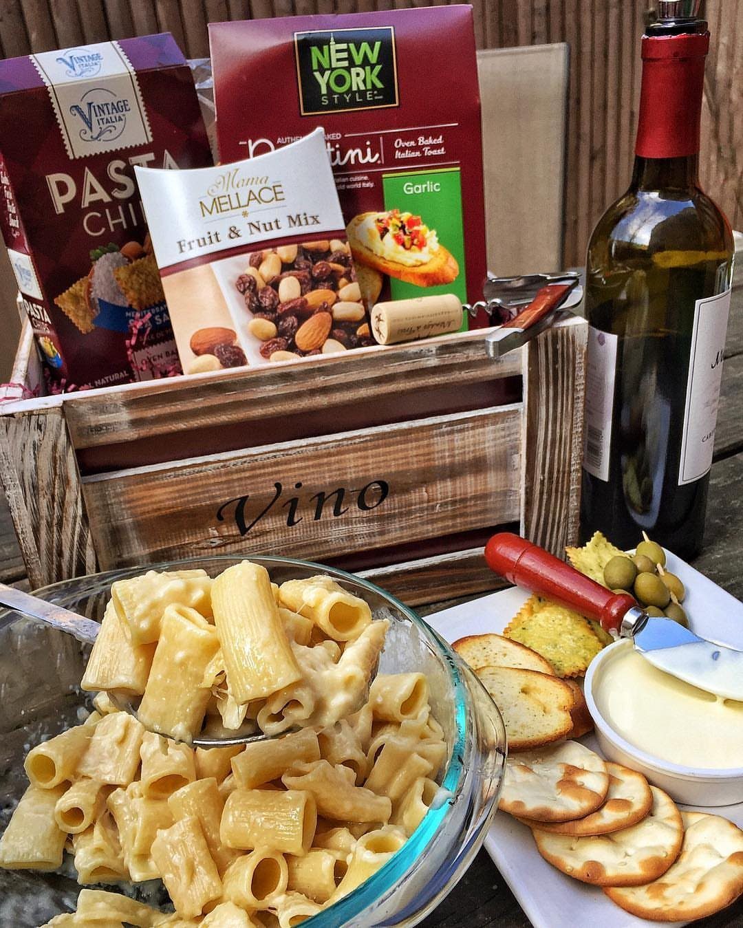 Wooden wine gift crate with pasta, snacks, and a bottle of white wine.