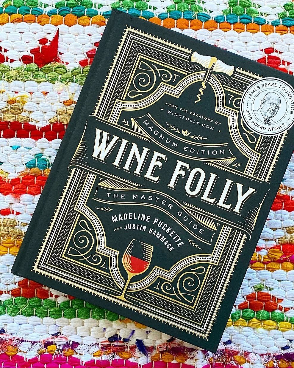10 Wine Gift Ideas for Every Kind of Wine Lover 5 Wine Folly Master Guide book with gold detailing on a colorful woven rug