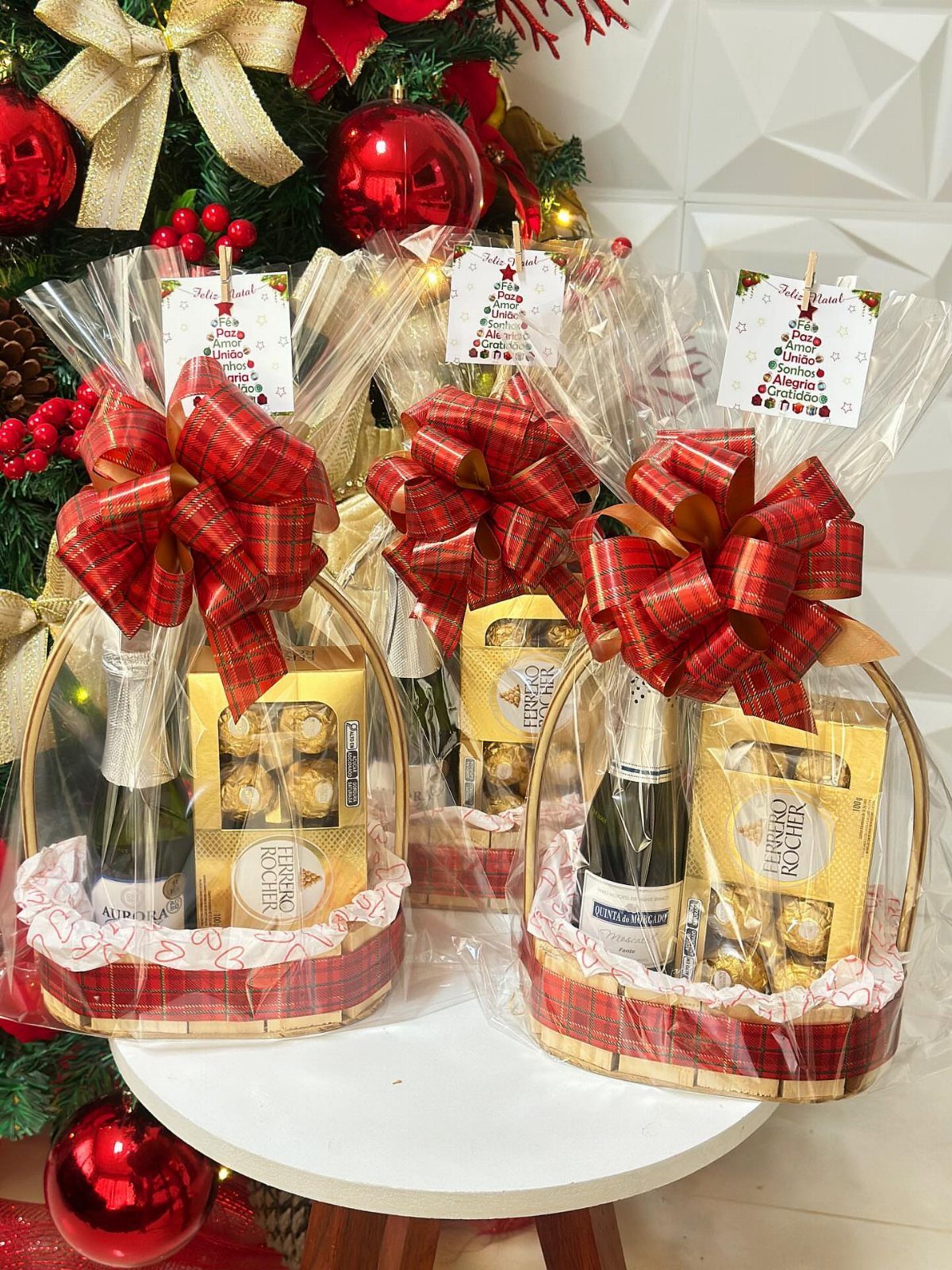 10 Wine Gift Ideas for Every Kind of Wine Lover 3 Three wine gift baskets with chocolates and red bows near a Christmas tree.